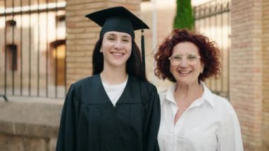 Two women mother and daughter celebrating graduation at campus university