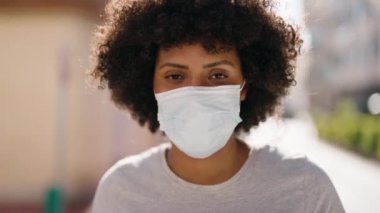 Young african american woman smiling confident wearing medical mask at street