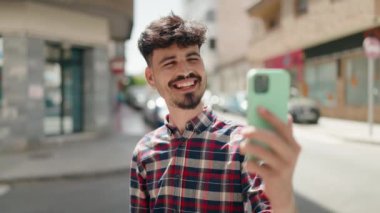Genç İspanyol adam gülümsüyor. Parkta kendine güvenen bir video çağrısı var.