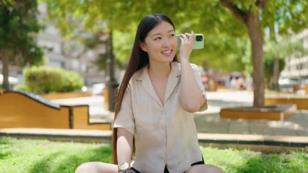 Chinese Woman Listening Audio Message Smartphone Sitting Grass Park — стокове відео