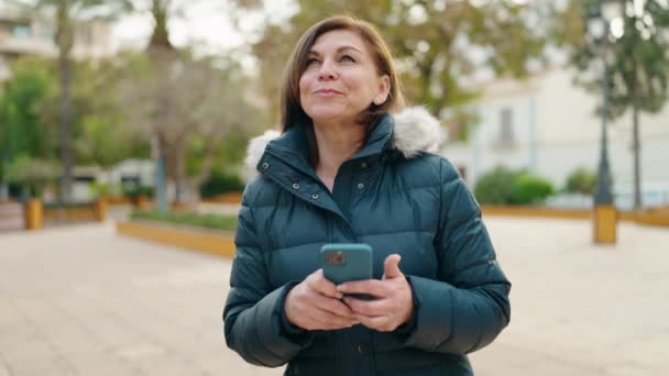 Parkta Akıllı Telefon Kullanan Orta Yaşlı Bir Kadın Gülümsüyor — Stok video