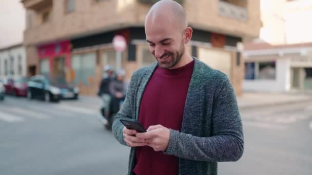 Junger Mann Mit Glatze Lächelt Selbstbewusst Mit Smartphone Auf Der — Stockvideo