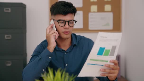 Молодой Латиноамериканец Работающий Ноутбуком Разговаривает Смартфоне Офисе — стоковое видео