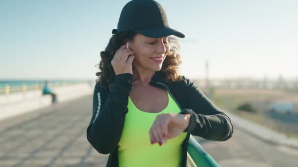 Middle Age Woman Wearing Sportswear Running Looking Stopwatch Seaside — Stockvideo