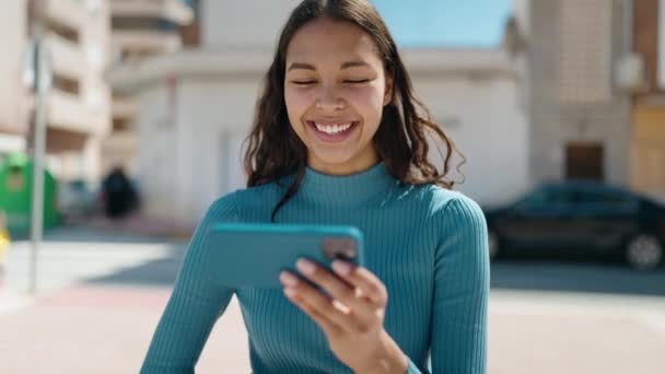 若いアフリカ系アメリカ人女性笑顔自信を持ってビデオを見ますスマートフォン上の通り — ストック動画
