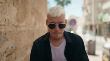 Young caucasian man smiling confident doing bad gesture with fingers at street