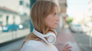 Young blonde girl smiling confident listening to music and dancing at street