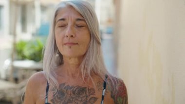 Orta yaşlı, kır saçlı, gülümseyen, kendine güvenen bir kadın.