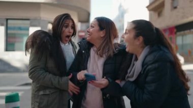 Mother and daughters smiling confident using smartphone at street
