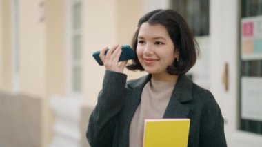 Genç İspanyol kız elinde kitapla caddedeki akıllı telefondan sesli mesaj dinliyordu.