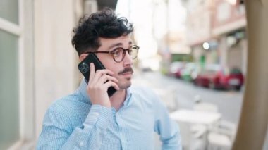 Genç İspanyol adam gülümsüyor. Kendine güveniyor. Sokakta akıllı telefondan konuşuyor.