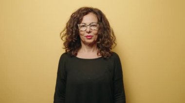 Middle age woman smiling confident holding cookie over eye over yellow background