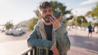 Genç İspanyol adam gülümsüyor. Kendine güveniyor. Sokakta akıllı telefondan konuşuyor.