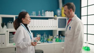 Man and woman scientists working high five with hands raised up at laboratory