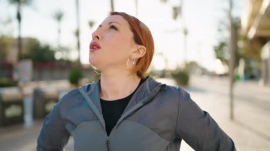 Young redhead woman wearing sportswear exhausted for running at street
