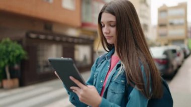 Adorable girl student writing on touchpad at street