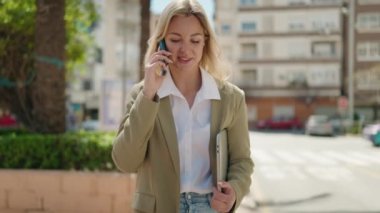 Young blonde woman executive talking on the smartphone at park