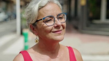 Middle age grey-haired woman smiling confident looking to the side at street
