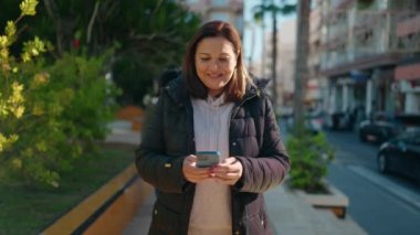 Mother and daughters using smartphone and hugging each other at park