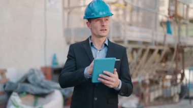 Young caucasian man architect with relaxed expression using touchpad at street