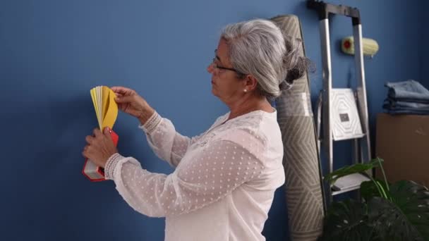 新しい家で壁をペイントする色を選択する中世の白髪の女性 — ストック動画