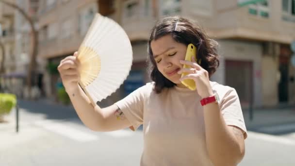 Νεαρή Γυναίκα Που Χρησιμοποιεί Handfan Μιλάει Στο Smartphone Στο Δρόμο — Αρχείο Βίντεο