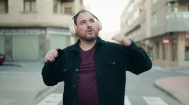 Young plus size man listening to music and dancing at street