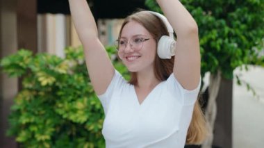 Young blonde woman smiling confident listening to music and dancing at street