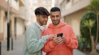 Genç İspanyol çift gülümsüyor. Caddedeki akıllı telefonun yanında özçekim yapıyorlar.
