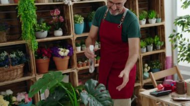 Middle age man florist using diffuser working at florist