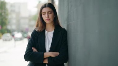 Genç İspanyol kız gülümsüyor. Kollarını kavuşturup caddede duruyor.