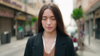 Young hispanic woman standing with relaxed expression at street