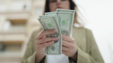 Young woman business worker counting dollars at street