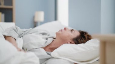 Middle age woman sleeping with pillow on head at bedroom