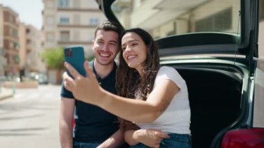 Genç bir çift şehirde akıllı telefonuyla selfie çekiyor.