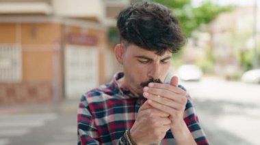 Young hispanic man smoking at street