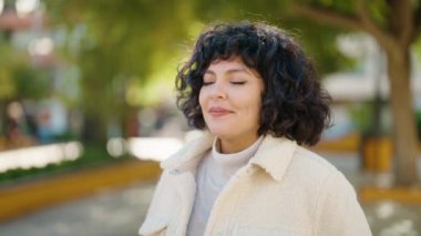 Genç İspanyol kadın gülümsüyor. Parkta nefes alıyor.