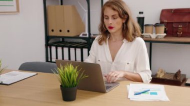 Young beautiful hispanic woman business worker using laptop reading document at office