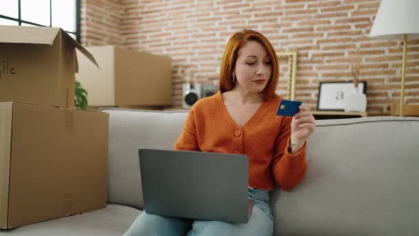 Jonge Roodharige Vrouw Met Smartphone Creditcard Zittend Bank Nieuw Huis — Stockvideo