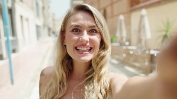 年轻的金发女人带着自信的笑容在街上打电话 — 图库视频影像