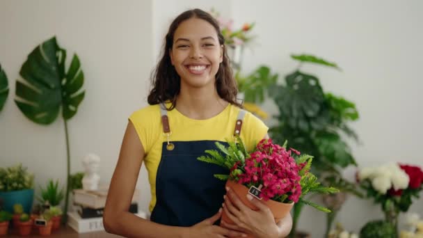 Young African American Woman Florist Smiling Confident Holding Plant Flower — Vídeo de stock