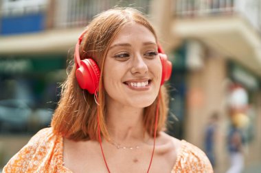Young redhead woman smiling confident listening to music at street