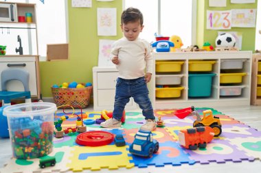 Adorable hispanic boy standing at kindergarten