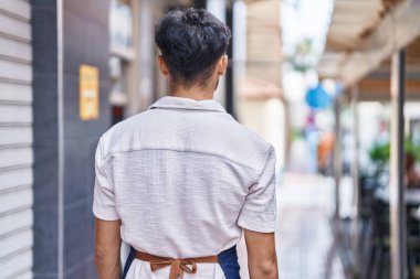Young arab man waiter standing on back view at restaurant