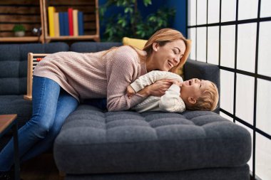 Mother and son hugging each other lying on sofa at home