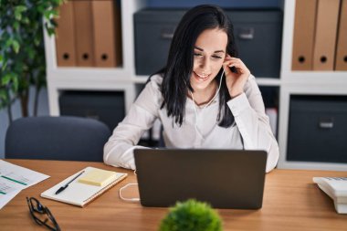 Young caucasian woman business worker using laptop and earphones working at office