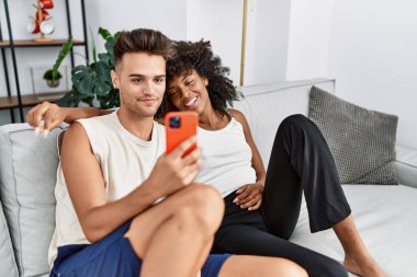 Kadın ve erkek, kendilerine güvenen gülümseyen bir çiftle evde kameranın önünde selfie çekiyorlar.