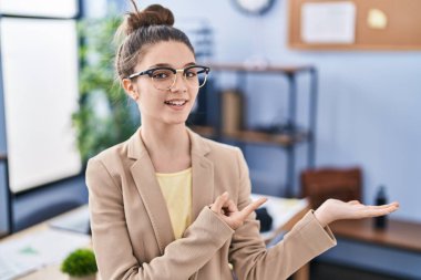 Ofiste çalışan gözlüklü genç kız kameraya hayret ediyor ve gülümsüyor.. 