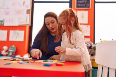 Teacher and student playing with maths puzzle game at kindergarten