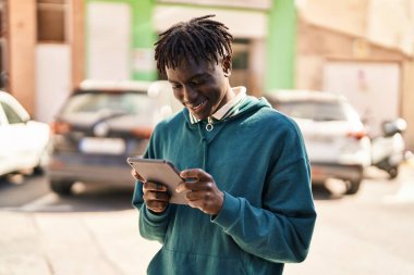 Sokakta dokunmatik ped kullanarak gülümseyen Afrikalı Amerikalı adam.